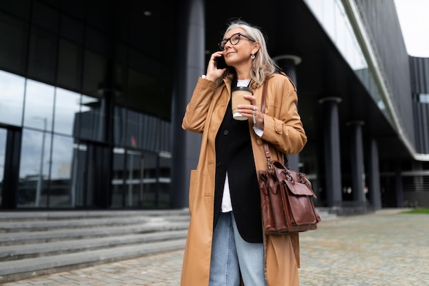 Mature successful woman talking on the phone next to the mall