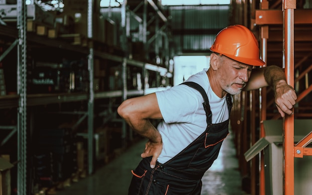 Mature Warehouse Worker with Backache in Workplace