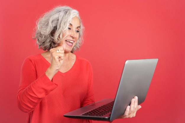 Mature woman celebrating while using a laptop