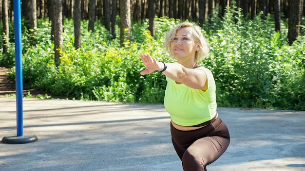 Mature woman does body stretching workout on sports ground