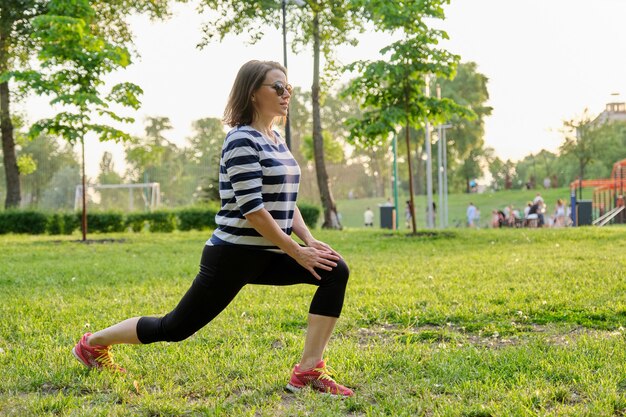 Mature woman doing fitness exercises in park. Active sports healthy lifestyle of middle-aged people, body and beauty