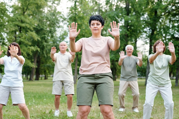 Mature woman exercising together with other people during training in the park