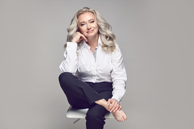 Mature woman in a fashionable casual clothes posing at studio Concept of happy aging