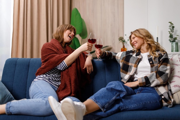 Mature woman and her daughter celebrating something and cheers glasses of wine