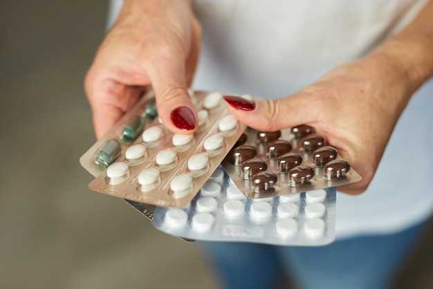 Mature woman hold in hand blister pack of pills