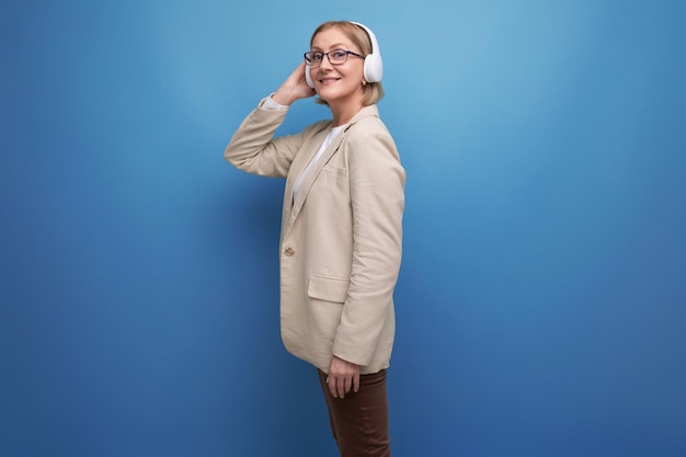 Mature woman in a jacket listening to music in wireless headphones