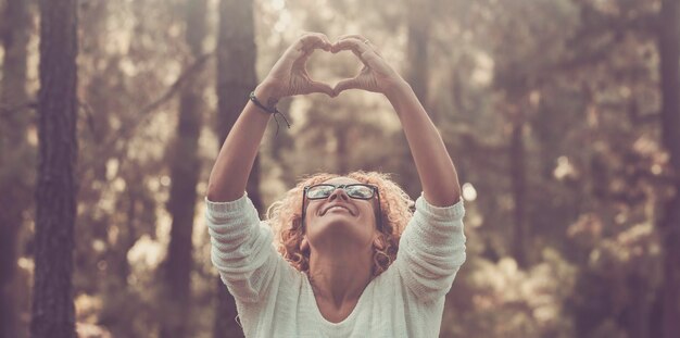 Photo mature woman making heart shape standing outdoors