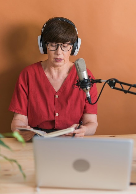 Mature woman making podcast recording for her online show Attractive business woman using headphones front of microphone for a radio broadcast