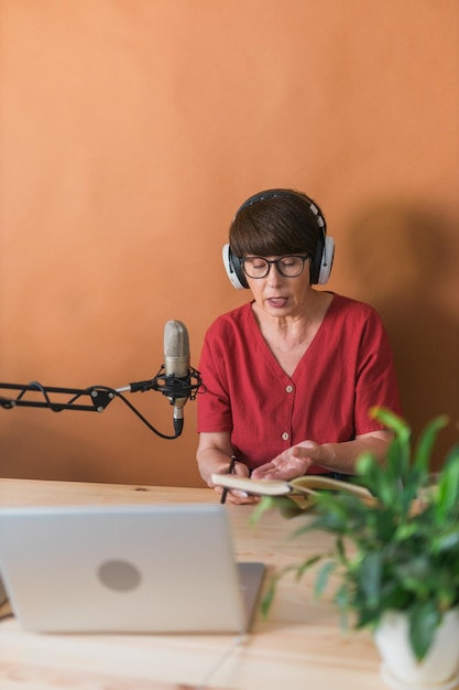 Mature woman making podcast recording for  online show attractive business woman using headphones