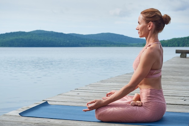 Mature woman in pink sportswear practices yoga The concept of a healthy lifestyle copy space for advertising