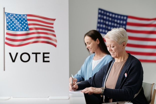 Mature woman putting tick sign opposite one of candidates in ballot paper