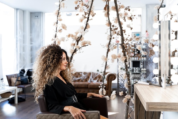 Mature woman sitting on a hairdresser salon in front of a mirror