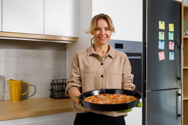 Mature woman took out a freshly baked pizza from the oven