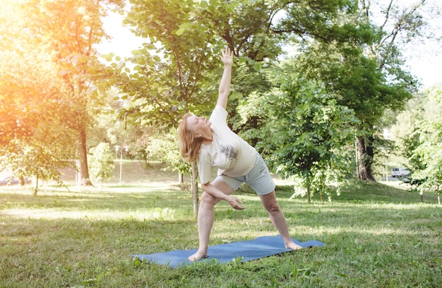 A mature woman in a Tshirt does fitness exercises and does yoga outdoors healthy lifestyle