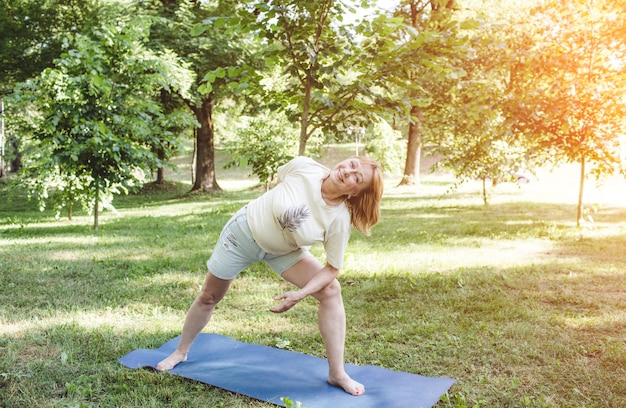 A mature woman in a Tshirt does fitness exercises and does yoga outdoors healthy lifestyle