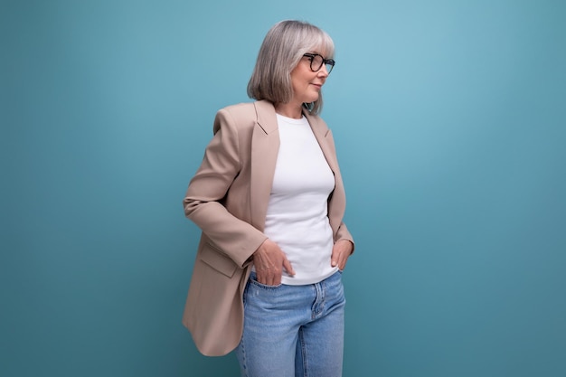 A mature woman with gray hair in a jacket stands confidently against a bright background with copy