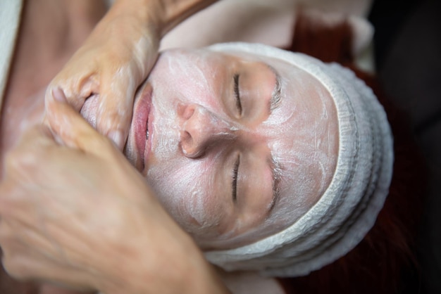 Mature woman with green eyes receiving a facial treatment