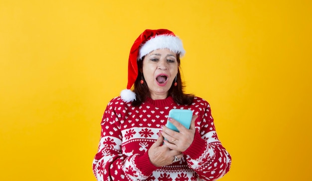 Mature woman with smartphone christmas yellow background