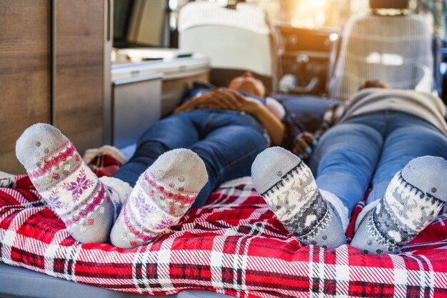 Photo mature women sleeping inside mini van camper wearing christmas warm socks focus on feet