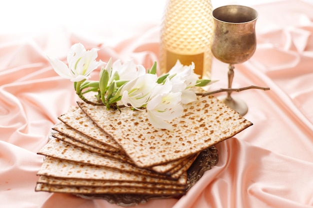 Matzo with white flowers wine and a glass on a pale pink background Pesach celebration concept jewish Passover holiday