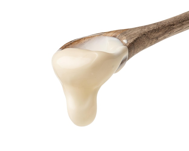 Mayonnaise sauce in a wooden spoon on a white background