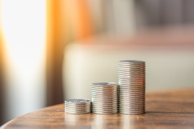 MClose up of stack of silver coins on wooden table.