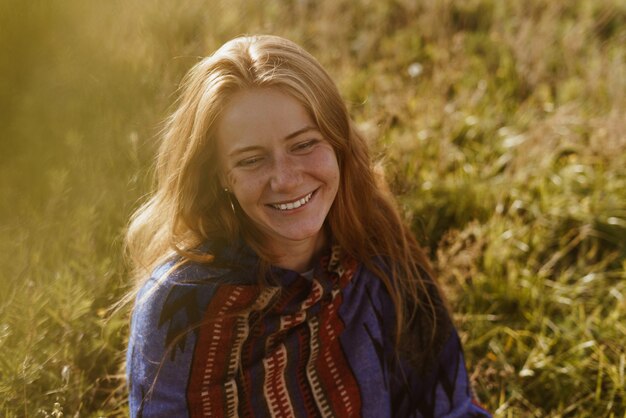 On the meadow grass sits beautiful in its natural beauty girl with wheat hair smiling broadly