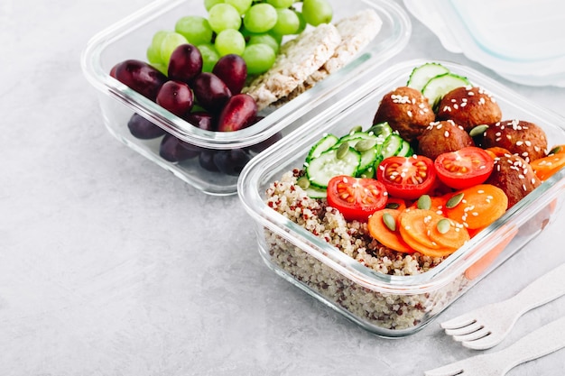 Meal prep lunch box containers with quinoa meatballs cucumbers carrots sesame and pumpkin seeds