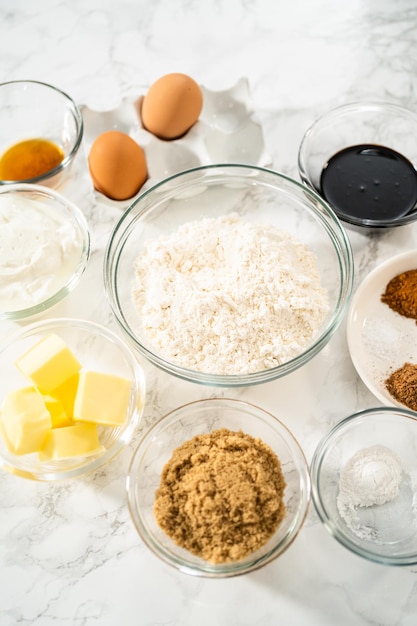 Measured ingredients in glass mixing bowls to bake gingerbread cupcakes