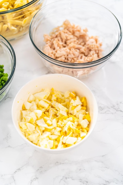 Measured ingredients in glass mixing bowls to make macaroni salad with chicken