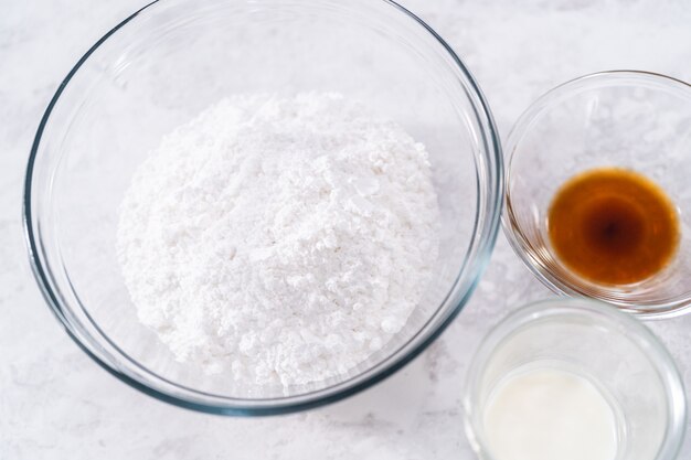 Measured ingredients in a glass mixing bowls to prepare the white glaze.