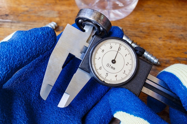 Measurement of the ball bearing inner diameter by a master in gloves with a slide caliper