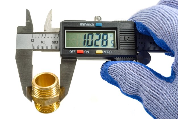 Measurement of plumbing fitting with digital caliper in masters hand in glove on white