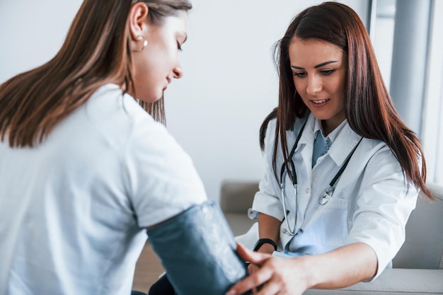 Measuring blood pressure Young woman have a visit with female doctor in modern clinic