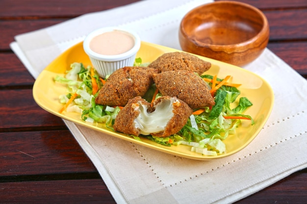 Meat Cheese Kubbe or Meat Cheese Kibbe with salad and dip served in dish isolated on table side view of middle east food