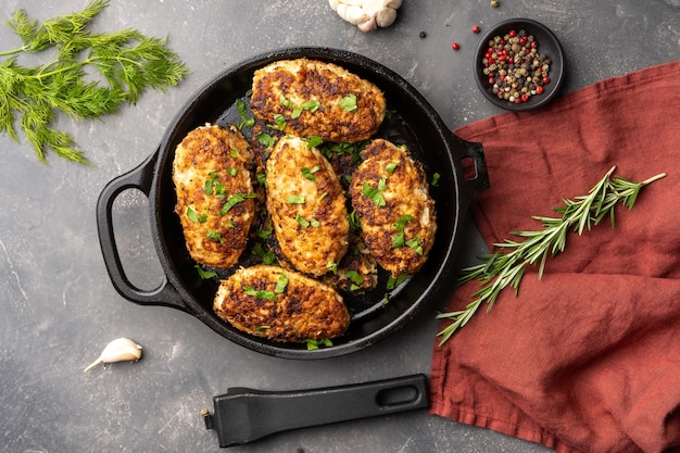 Meat cutlets in frying pan over background herbs and spices top view flat lay high quality photo