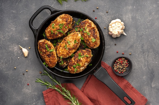 Meat cutlets in frying pan over background herbs and spices top view flat lay high quality photo