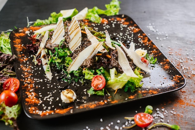 Meat dish with cheese and vagetables on black background