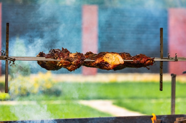 Meat from pork prepares on a skewer on the fire in the yard in the summer. Smoke gives piquancy to meat