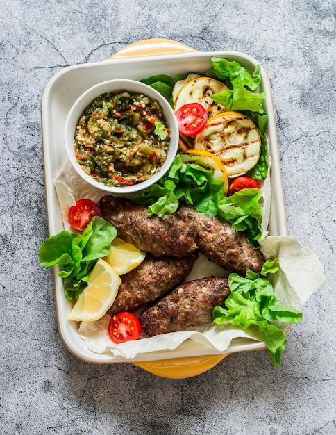 Meat kebab grilled vegetables sauce zucchini flatbread green salad a delicious mediterranean style lunch on a gray background top view