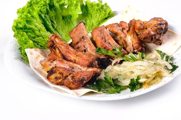 Meat kebab on ribs on lavash with onions and cabbage on a white plate, on an isolated white background