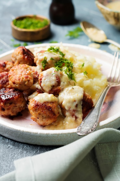 Meat meatballs with mashed potatoes, dill and cream sauce on a tight gray stone or concrete