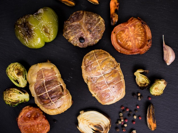 Meat products grilled and grilled vegetables on a dark background