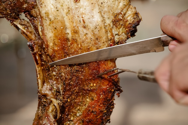 Meat roast and cut on the table and campfire with gaucho style firewood