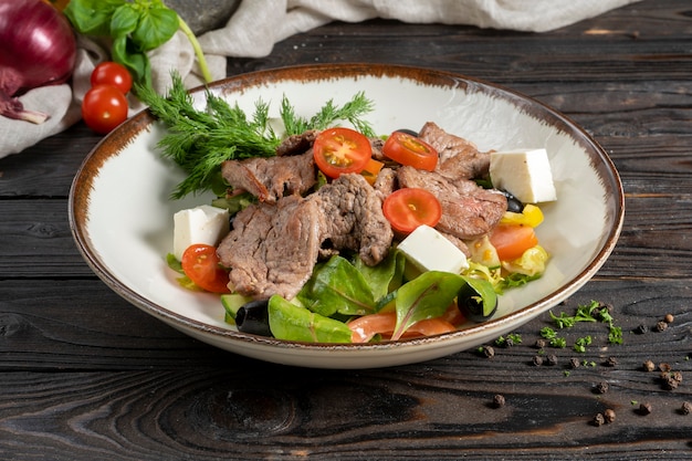 Meat salad with roast beef, lettuce leaves, cherry tomatoes, feta cheese and olives.