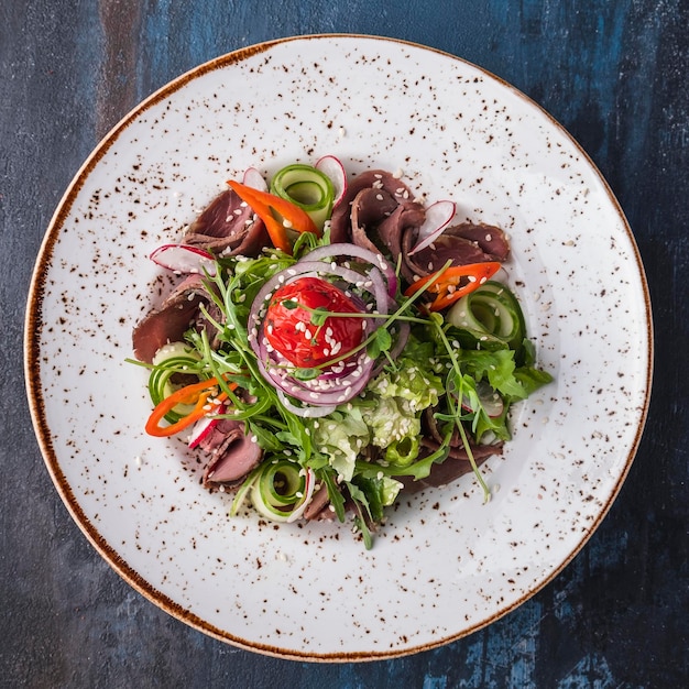 Meat salad with roast beef and vegetables on a plate Top view