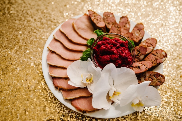 Meat sausage bacon is cut into thin pieces with horseradish on a plate Festive menu on the table Top view Close up Delicious food