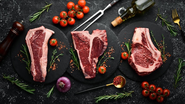 Meat Set of raw steaks tbone tomahawk striploin tenderloin new york steak Flat lay top view on black stone cutting table