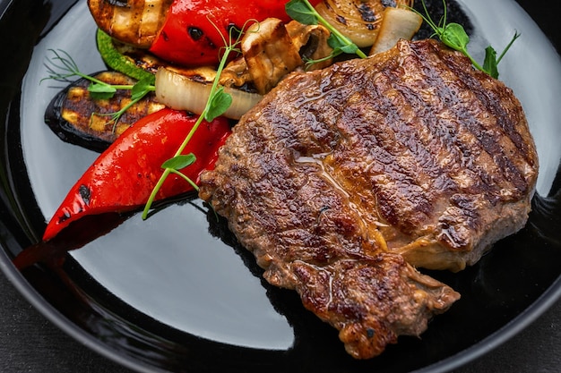 Meat steak with grilled vegetables on a dark background