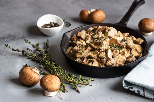 Meat stewed with mushroom and thyme in a cast iron pan